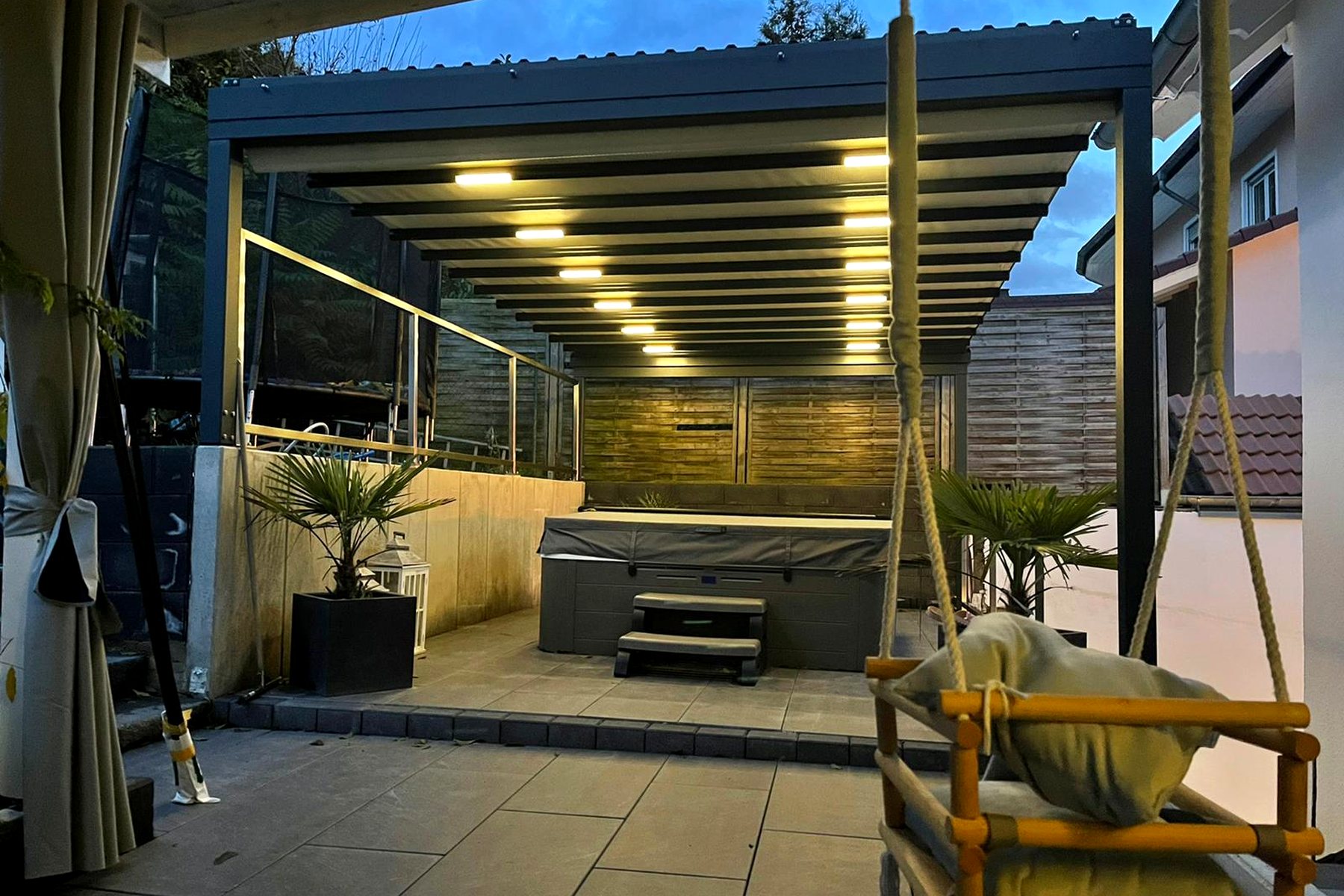Beleuchtete Pergola-Überdachung mit Lounge-Möbeln und warmem LED-Licht am Abend