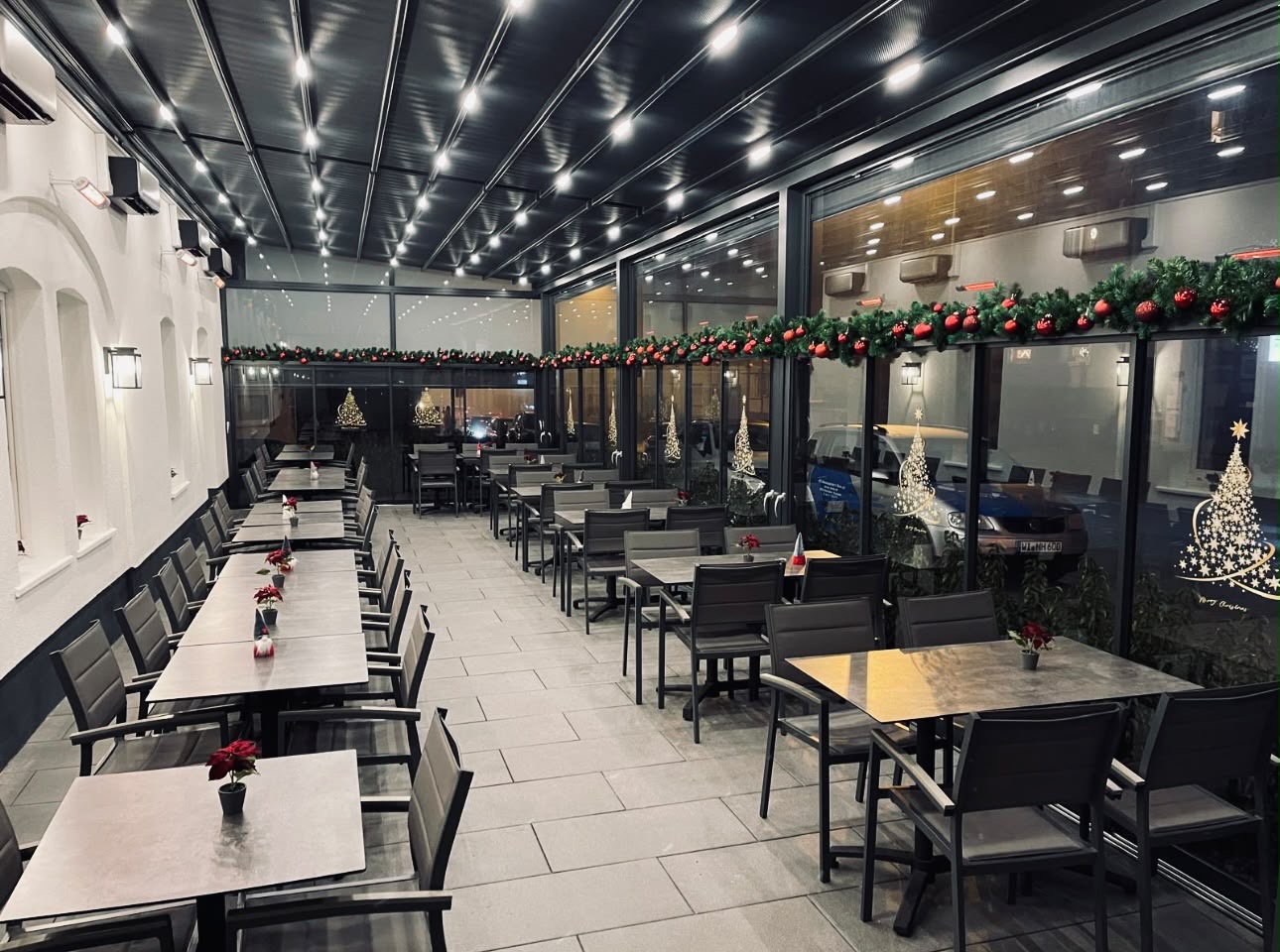Überdachte Gastronomieterrasse mit Tischen, Stühlen und integrierter Deckenbeleuchtung